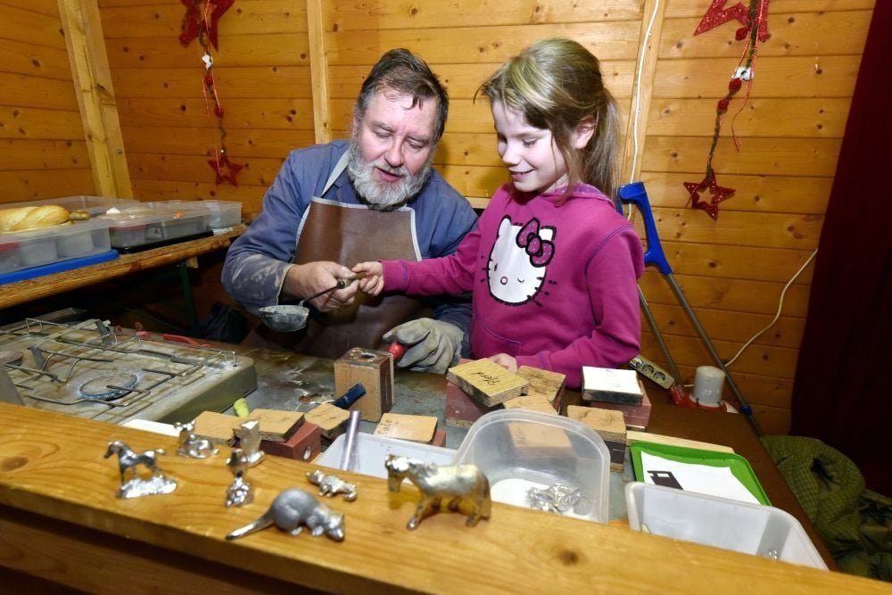 Ingo Schneppel zeigt der siebenjährigen Tessa-Elisabeth, wie man mit einem Gießtiegel umgeht.