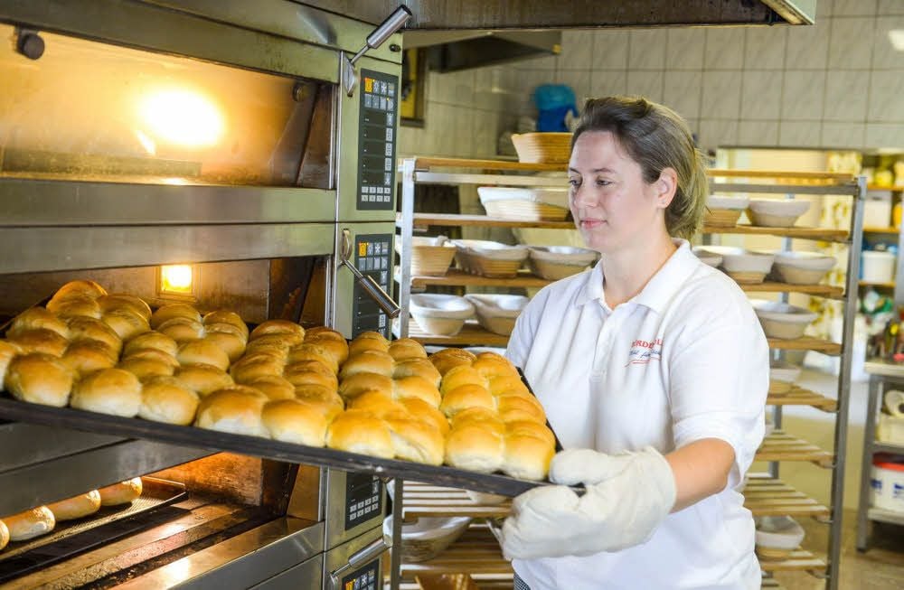 Bäckermeisterin Elisabeth Elze holt die frischen, duftenden Semmeln aus dem Backofen.