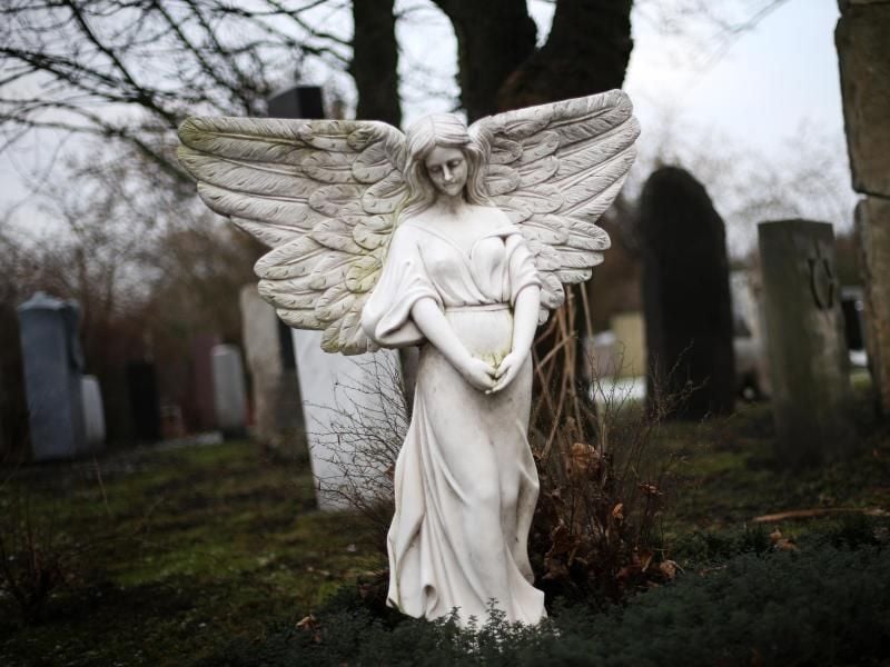 Eine Engelsfigur als Grabstein steht auf einem Friedhof. Foto: Christian Charisius/Archiv