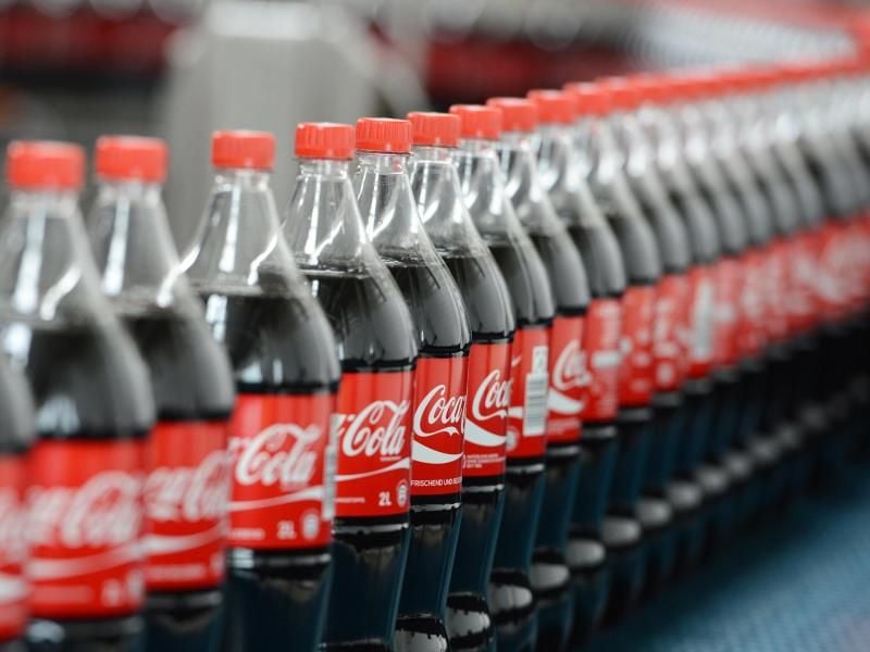 Coca-Cola-Flaschen auf einem Transportband. Foto: Jens Kalaene/Illustration