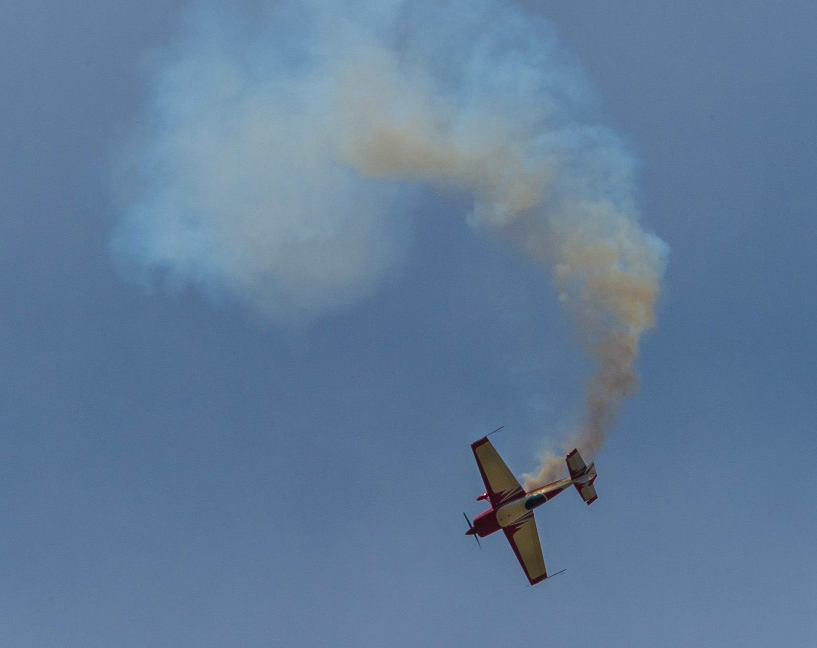 Ein Kunstflieger setzt über dem Flugplatz Ballenstedt während eines Flugmanövers gezielt Rauch ein.