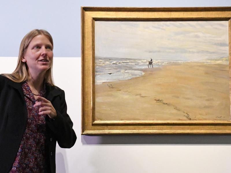 Die Kuratorin der Ausstellung, Karoline Feulner, erläutert das bislang verschollene Bild von Max Slevogt mit dem Titel „Strandbild mit Muschelfischer”. Foto: Peter Zschunke