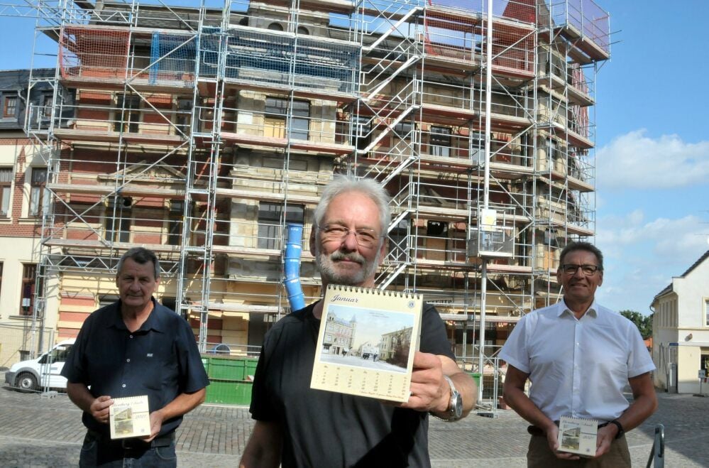 Winfried Becker (von links), Michael Koch und Peter Löbus präsentieren den neuen Jahreskalender 2021 des Lionsclubs Bernburg vor dem Theatercafé, das derzeit saniert wird, und dessen alte Ansicht das Januar-Blatt ziert.