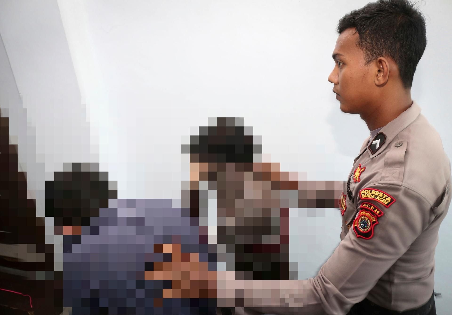 Ein indonesischer Polizist und die beiden Angeklagten.