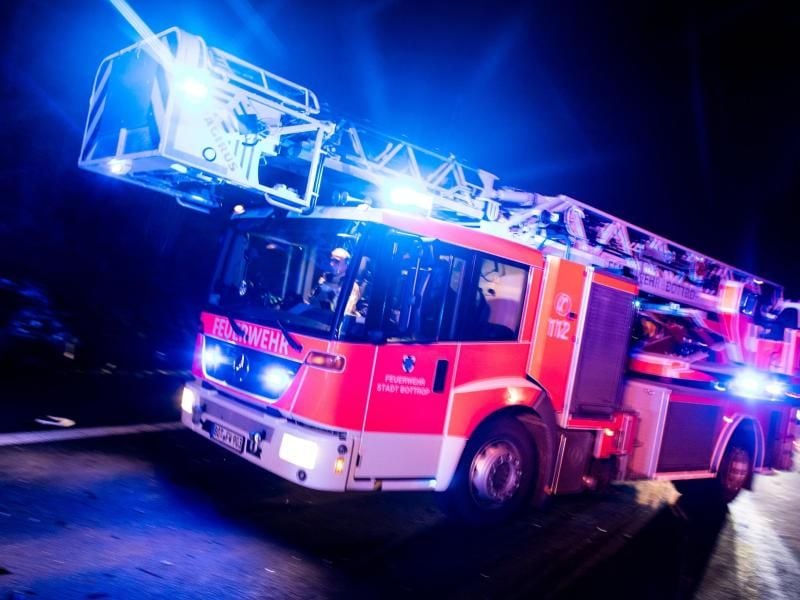 Ein Drehleiterwagen der Feuerwehr fährt mit Blaulicht an einer Unfallstelle vorbei. Foto: Marcel Kusch/dpa/Illustration