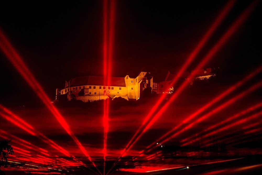 Die Neuenburg über einer mitternächtlichen Sonne: Nicht der Widerschein der Unterwelt, sondern die Laserperformance zur Lichternacht.