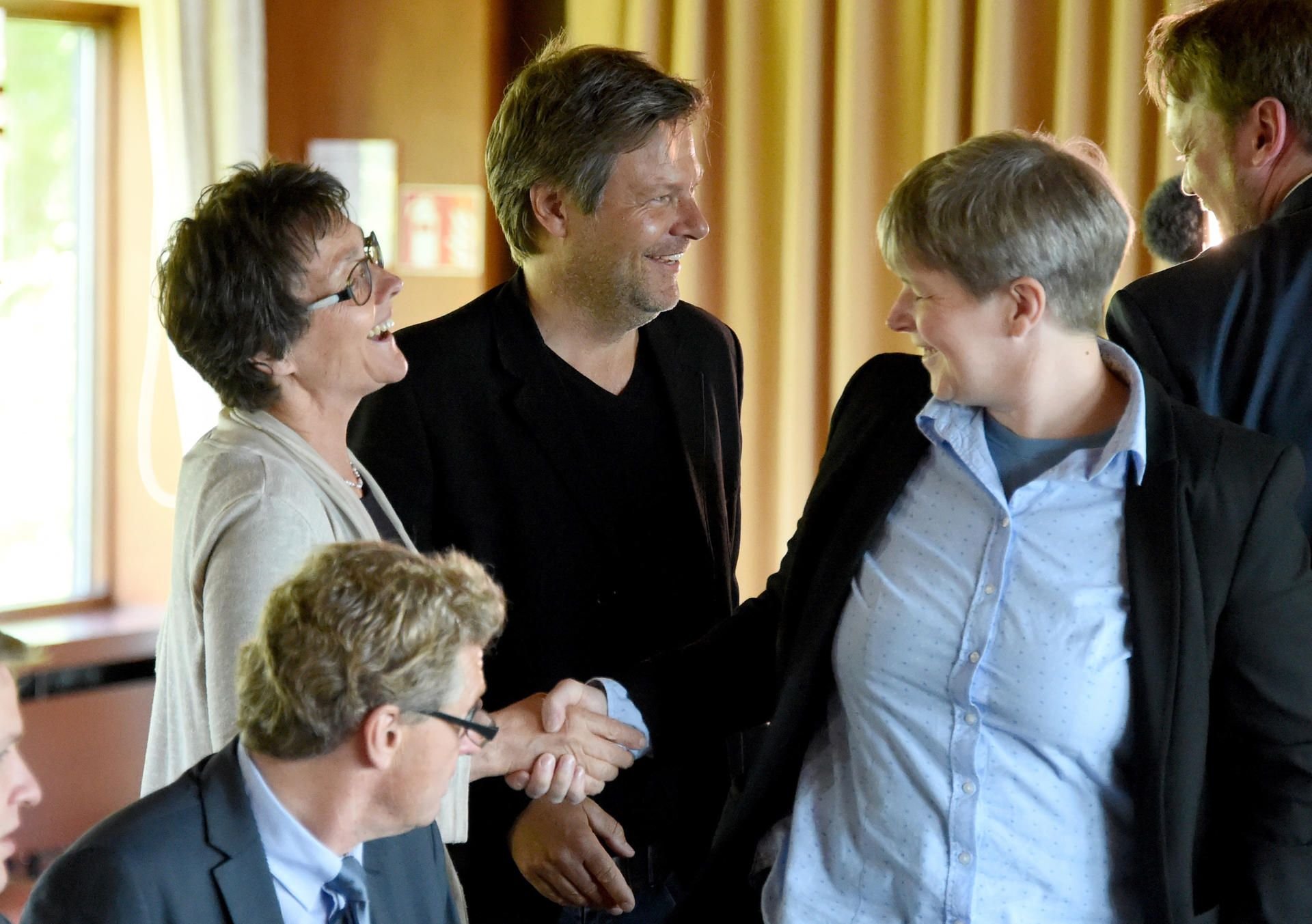 Monika Heinhold und Robert Hack von den Grünen begrüßen die FDP-Politikerin Britta Reimers (rechts). Vorne sitzt Bernd Buchholz, ebenfalls Politiker der Liberalen.