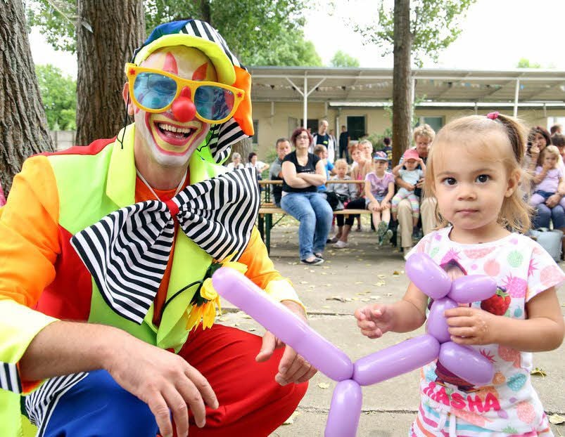 Jens Hartmann als Clown Beppo bastelt für Miriam ein Luftballontier.