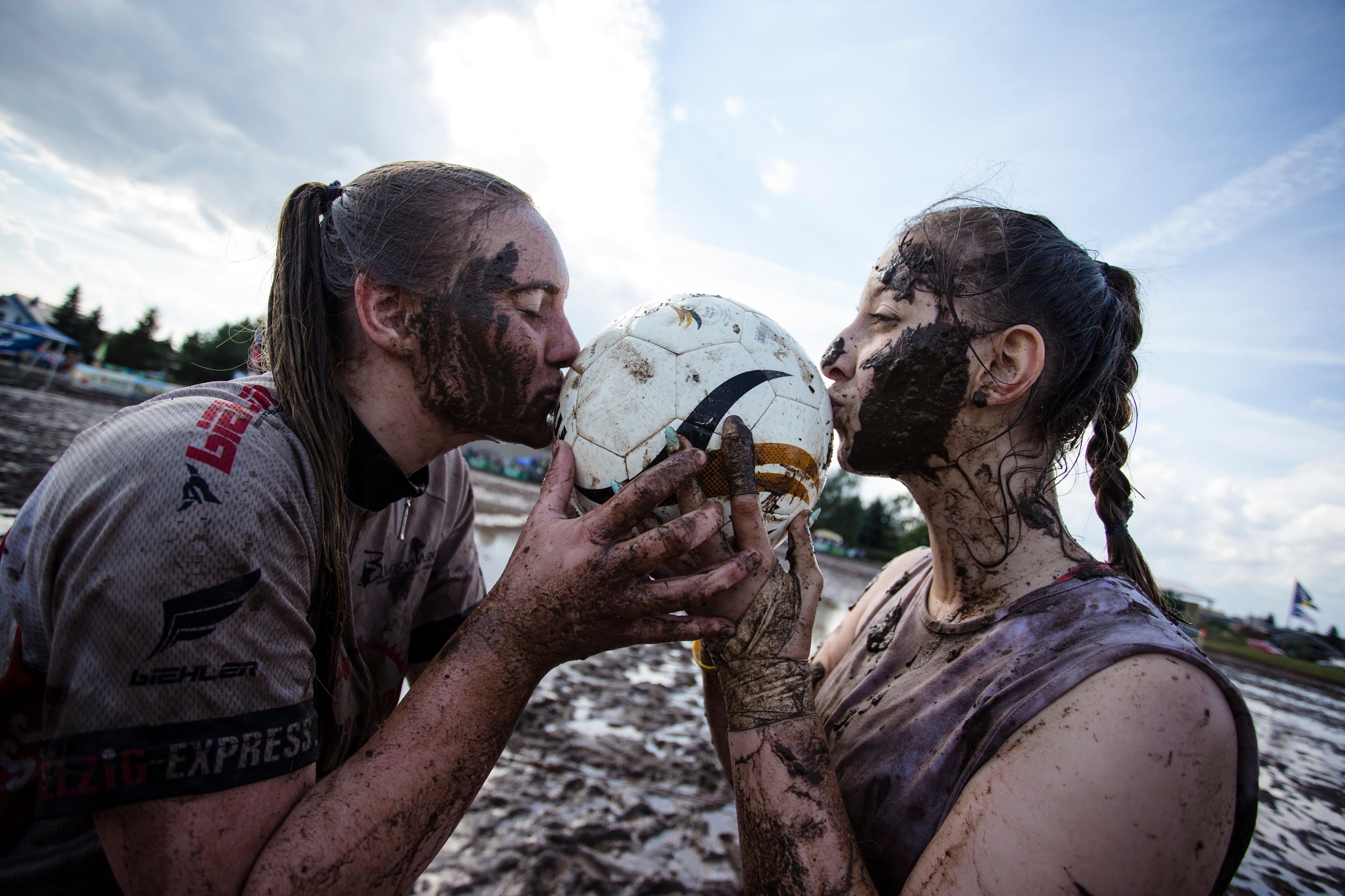 Cecile Rüdiger (l) und Sandra Schäfer, Spielerinnern der "Hallzig Fighters" aus Eilenburg, küssen bei den Deutschen Meisterschaften im Matschfußball.