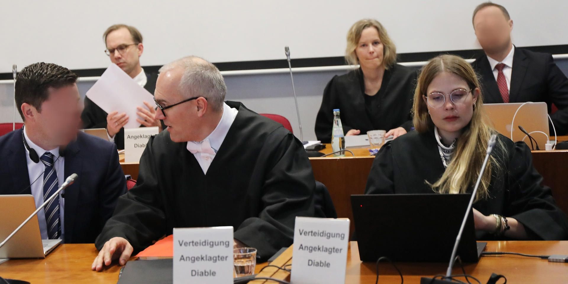 Die Angeklagten (l.) und (hinten r.) sitzen beim Prozess um die Cum-Ex-Deals im Landgericht Bonn neben ihren Anwälten.