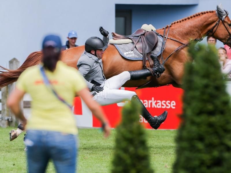 Der Reiter Philipp Weishaupt fällt von seinem Pferd Che Fantastica herab. Foto: Rolf Vennenbernd/Archivbild