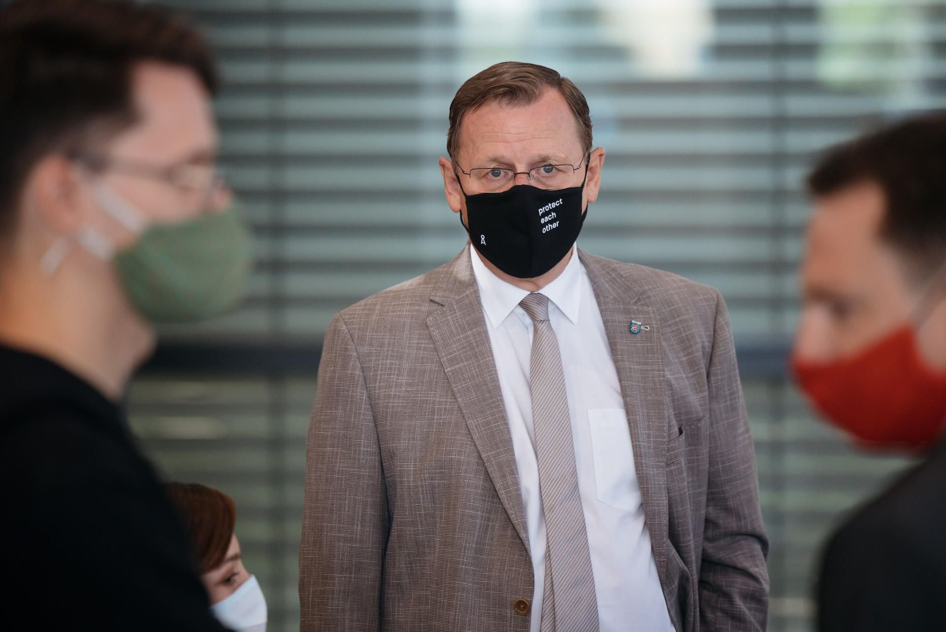 Bodo Ramelow (M, Linke), Ministerpräsident von Thüringen, spricht im Landtag mit Mundschutz mit anderen Abgeordneten der Linke-Fraktion.