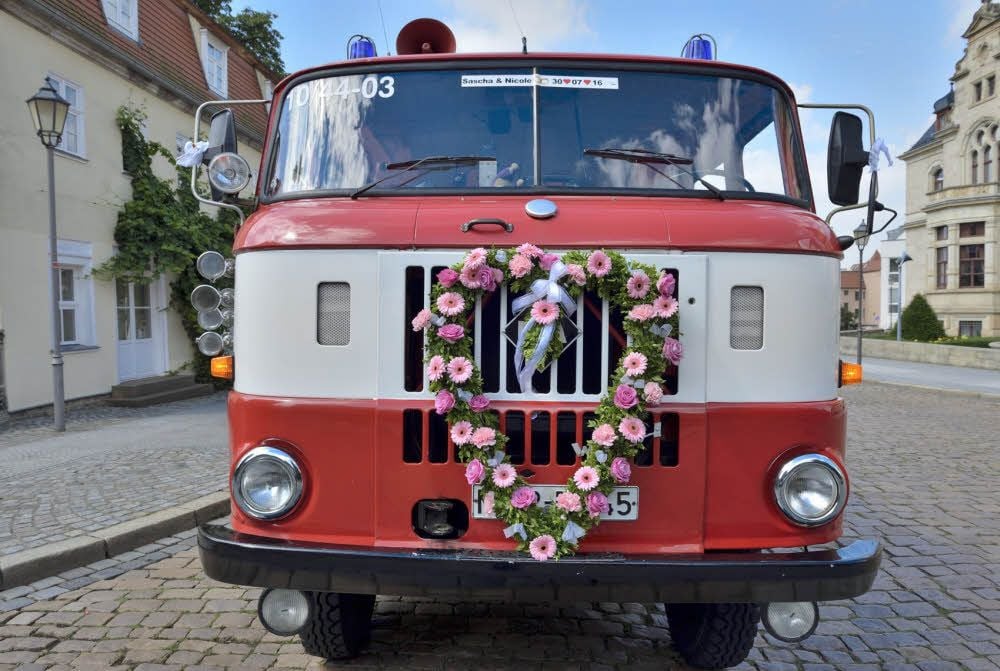 Das alte Löschfahrzeug mit Blumenherz diente als Hochzeitskutsche.