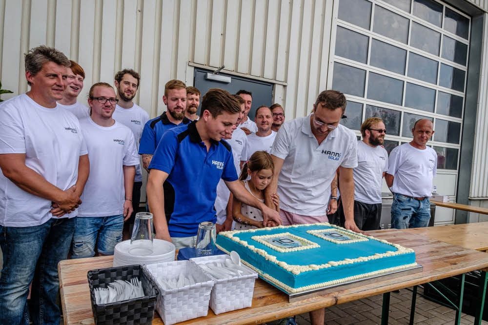 Die Jubiläumstorte wird vom neuen Geschäftsführer Markus Jahn (blaues Shirt) und seinem Vorgänger Daniel Hannemann angeschnitten.