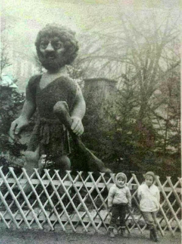 Kinder stehen vor einer Figur eines Riesen aus dem Märchenwald des Hettstedter Weihnachtsmarktes.