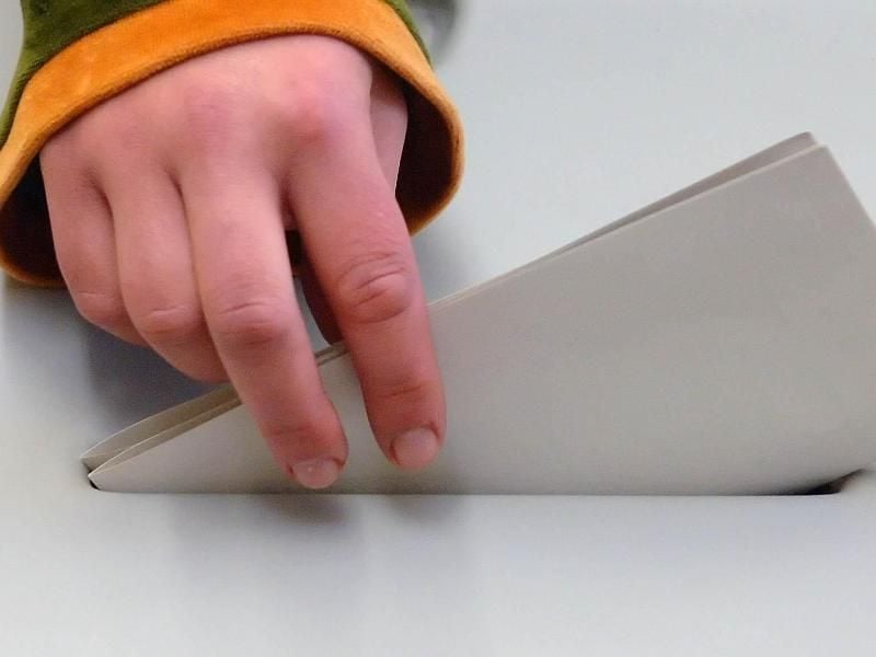 Eine Hand steckt einen Stimmzettel in eine Wahlurne. Foto: Peter Endig/Archiv