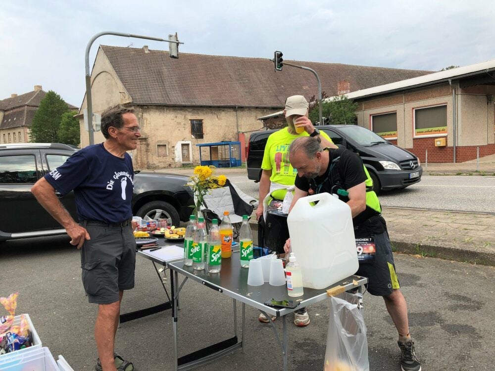 Streckenposten Theo Steinbacher hält in Emseloh alles bereit, um die Kraftreserven der Läufer wieder aufzutanken. Hier sind es Danny Reinhold (Mitte) aus Bremen und Manfred Kranz (rechts) aus München, die sich bei der Hitze am Wasser bedienen.