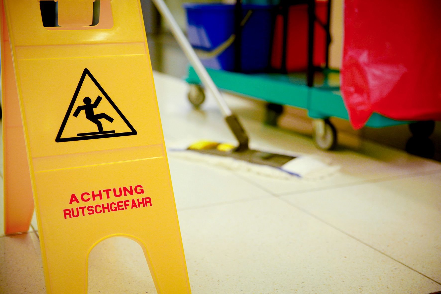 Ein Angestellter einer Reinigungsfirma wischt den Fußboden.