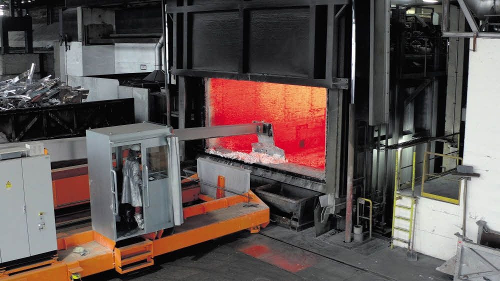 Ein Blick in die Hydro-Gießerei: Ein Arbeiter in einer Schutzkanzel zieht bei etwa 700 Grad Celsius Schlacke vom flüssigen Aluminium aus dem Schmelzofen ab.