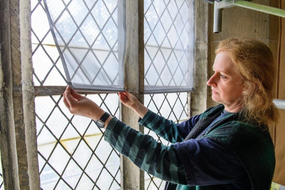 Restauratorin Andrea Himpel bringt an einem der Fenster der Moritzkirche den Aluminium-Stoff an.