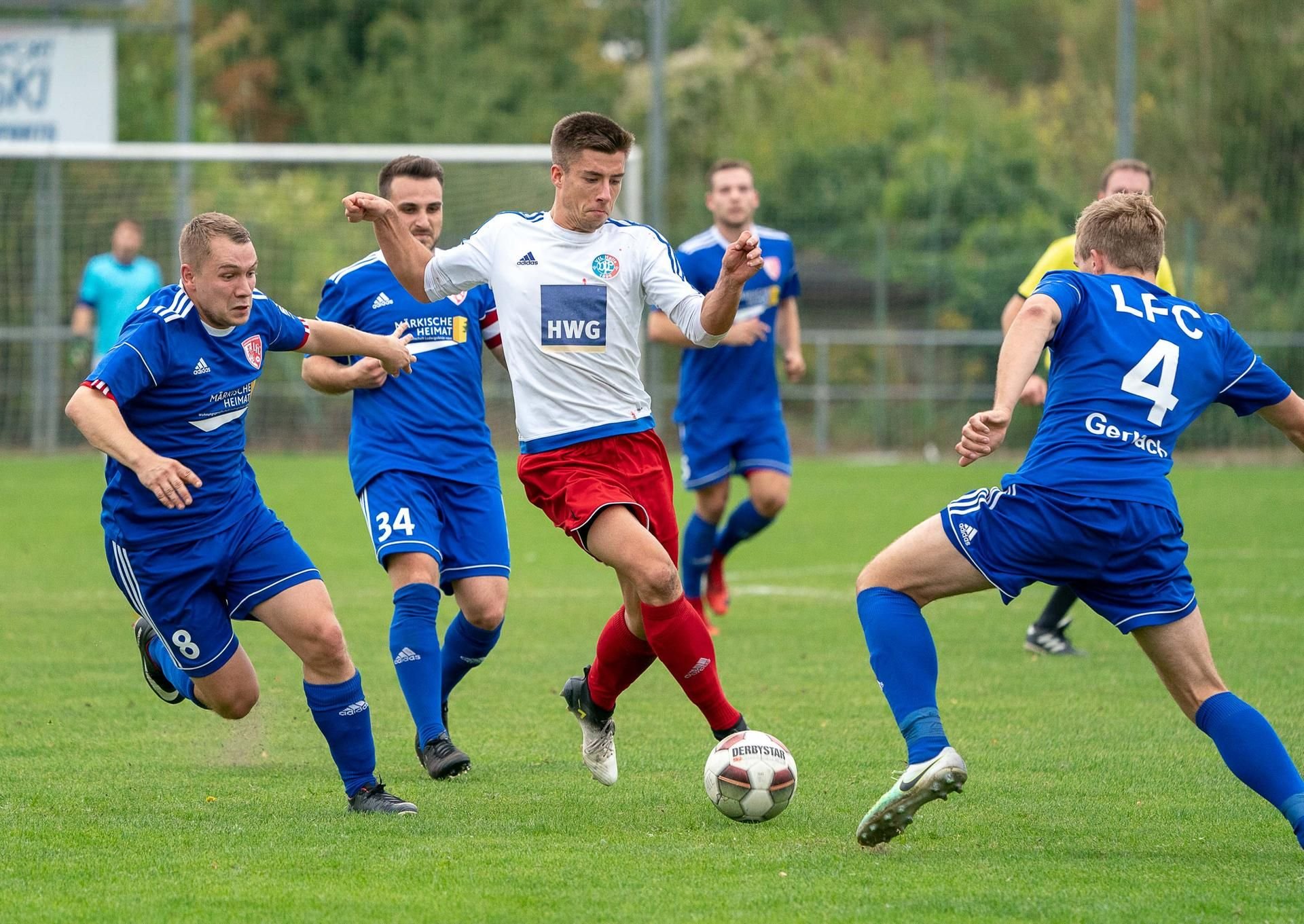 Halles Lukas Englich (M.) gegen drei Ludwigsfelder im Spiel der Fußball-Oberliga.