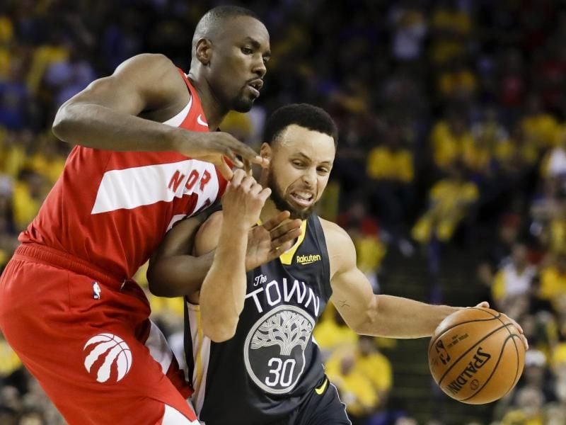 Stephen Curry (r) von den Golden State Warriors behauptet sich gegen Serge Ibaka von den Toronto Raptors. Foto: Ben Margot/AP