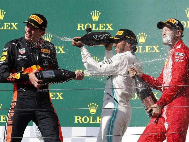 Champagnerdusche: Sieger Lewis Hamilton (M) mit Max Verstappen (l) und Sebastian Vettel auf dem Podium in Budapest. Foto: Laszlo Balogh/AP