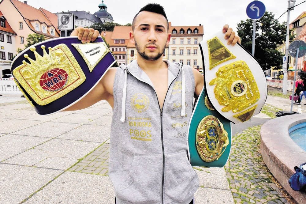Voller Stolz präsentiert Sascha Kerimov seine drei Titel-Gürtel auf dem Weißenfelser Marktplatz.