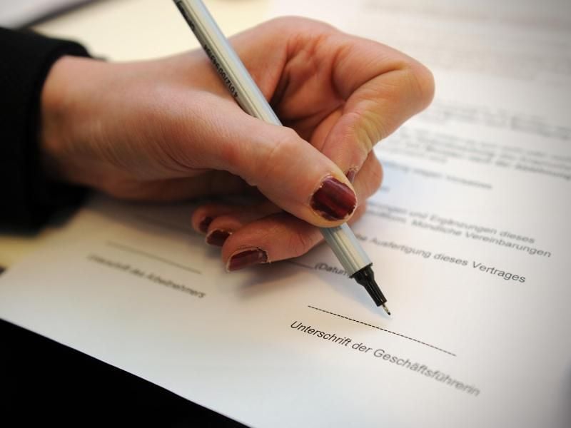 Eine Frau unterschreibt einen Arbeitsvertrag. 7900 Mitarbeiter arbeiten mit befristeten Arbeitsverträgen für die Bundesregierung. Foto: Jan-Philipp Strobel