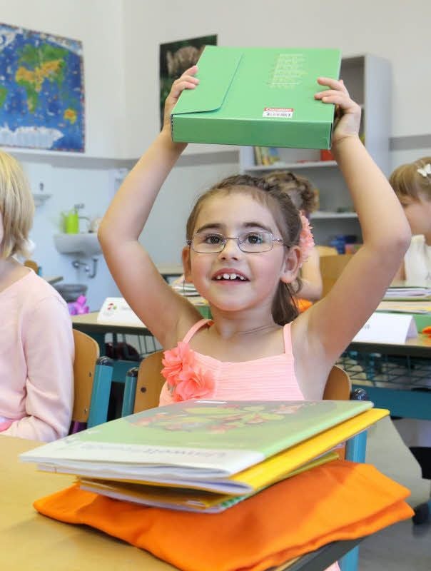 Hurra, ich bin ein Schulkind! Bei der Kennenlernrunde im Klassenraum nimmt Jasmin die Unterrichtsmaterialien in die Hand, mit denen ab Montag gelernt wird.