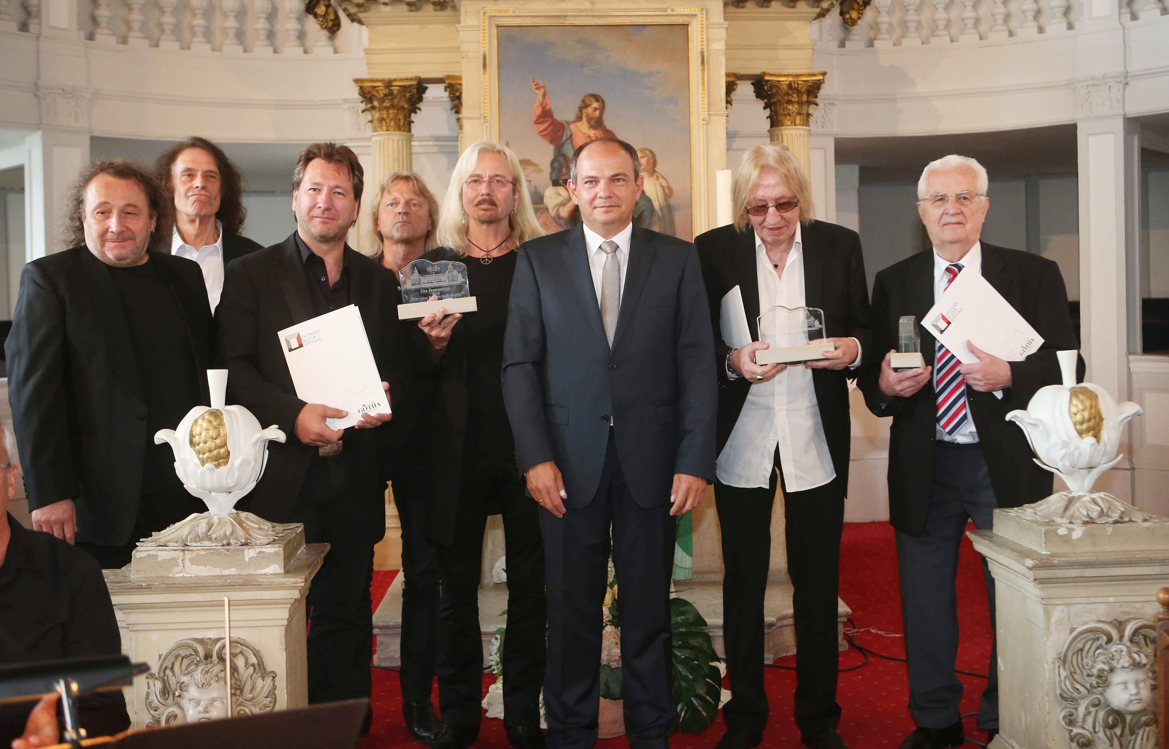 Die Preisträger der Gruppe Karat, Martin Becker, Christian Liebig, Sänger Claudius Dreilich, Michael Schwandt, Bernd Römer, Gothas Oberbürgermeister Knut Kreuch (SPD), Komponist Ulrich Swillms und Texter Helmut Richter (l-r) posieren mit dem Kulturpreis Der Friedenstein in der Kirche von Schloss Friedenstein in Gotha (Thüringen).
