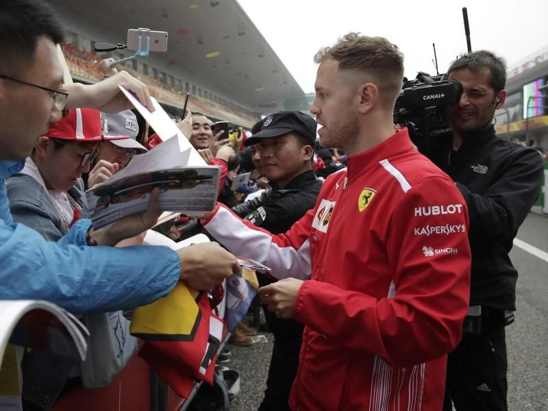 Sebastian Vettel gibt am Streckenrand in Shanghai seinen Fans Autogramme. Foto: Andy Wong/AP