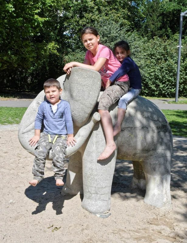 Armir (vier Jahre), Radima (zehn Jahre) und Lesina (fünf Jahre) haben Spaß beim Klettern auf dem Stadtpark-Elefanten.