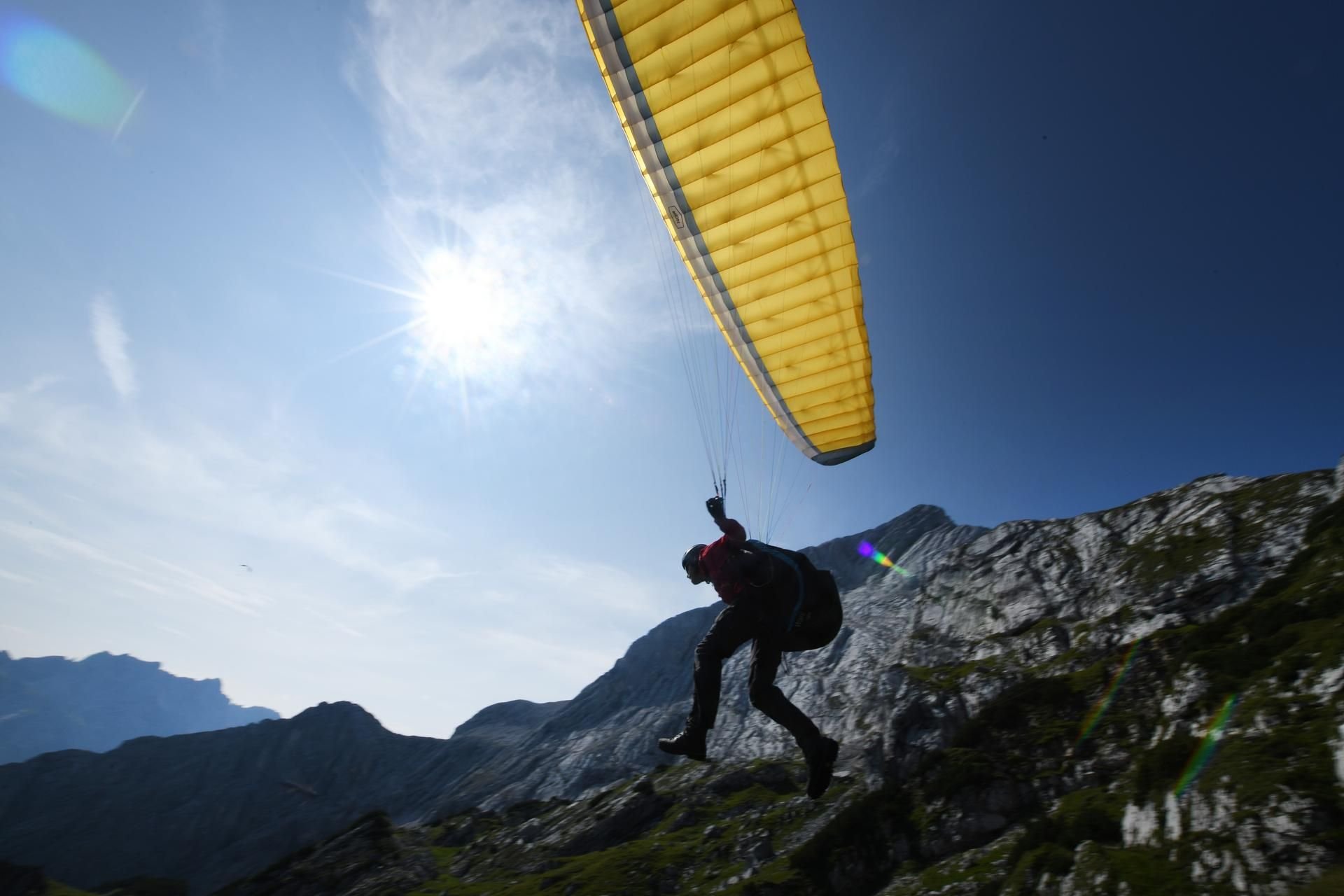 Ein Gleitschirmflieger startet bei sonnigem Wetter in den Alpen. (Symbolbild)