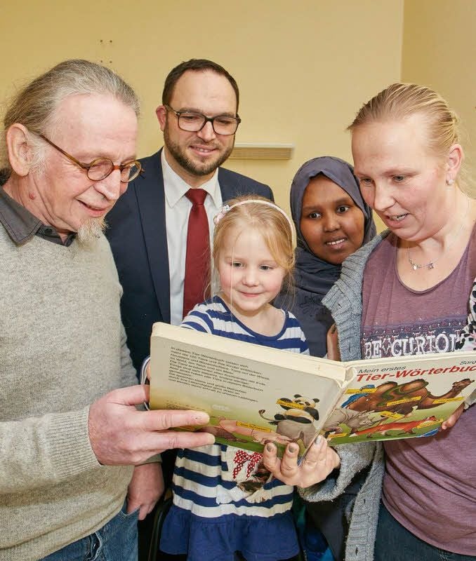 Vereinschef Hans Strecker (von links) und Klinikumsdirektor Torsten Jörres erklären Ida und Karen Richter sowie Fadumo Muhydin Noor mit Hilfe eines Buches, welche Tiere es gibt.