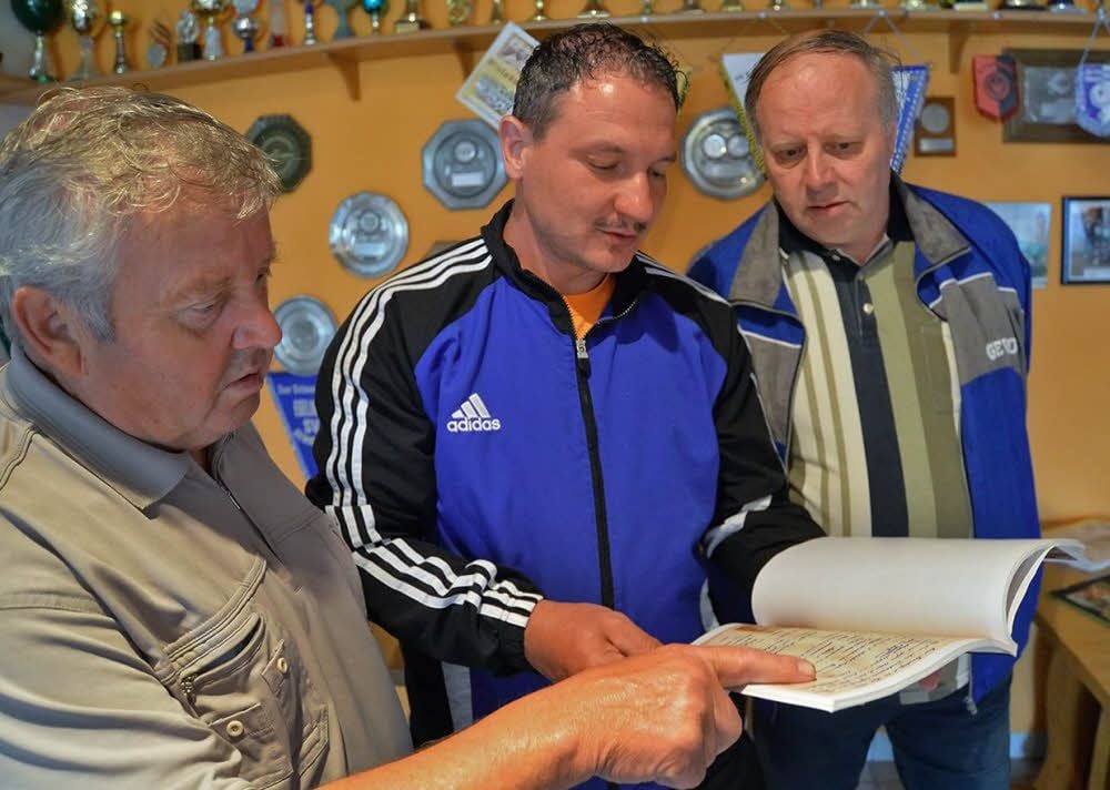 Günter Wiedemann, Thomas Senier und Volker Teuke (von links) schauen sich die Chronik an.