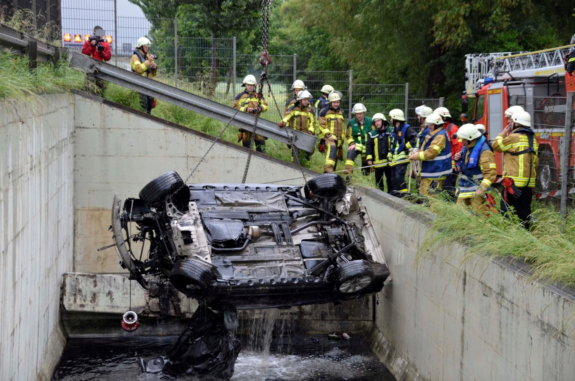 Feuerwehrleute bergen das Auto aus dem Regenrückhaltebecken.