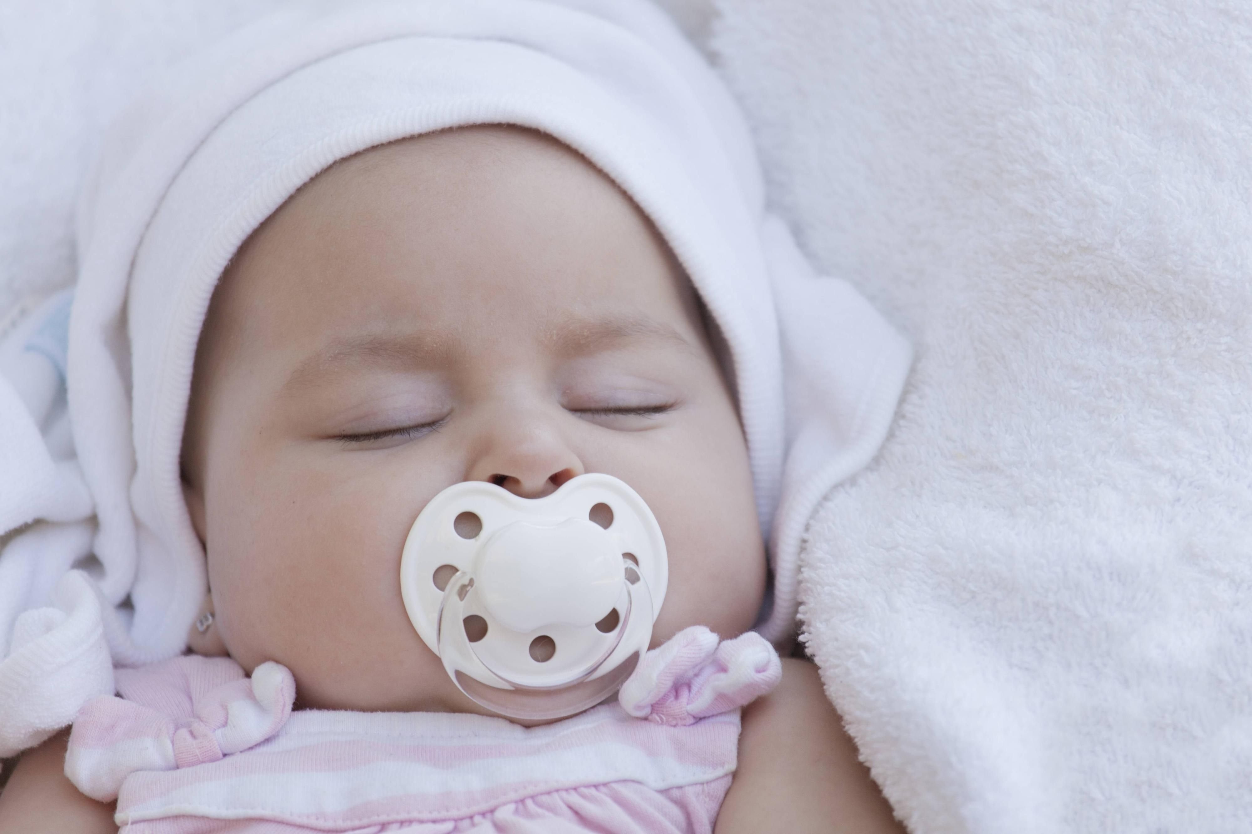 Baby schläft mit Schnuller im Mund.