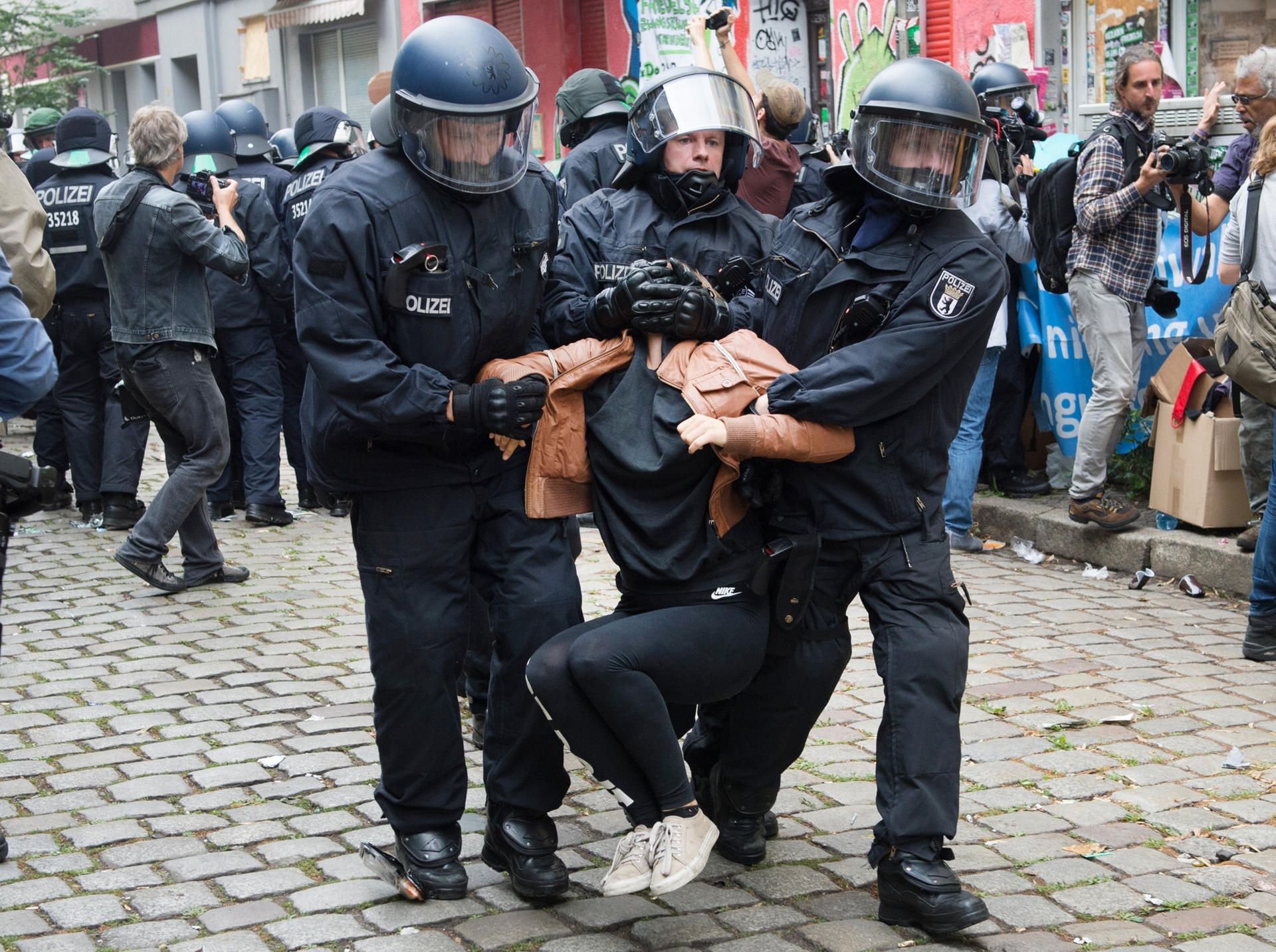 Polizisten tragen in Berlin Demonstranten auf der Friedelstraße in Neukölln weg.