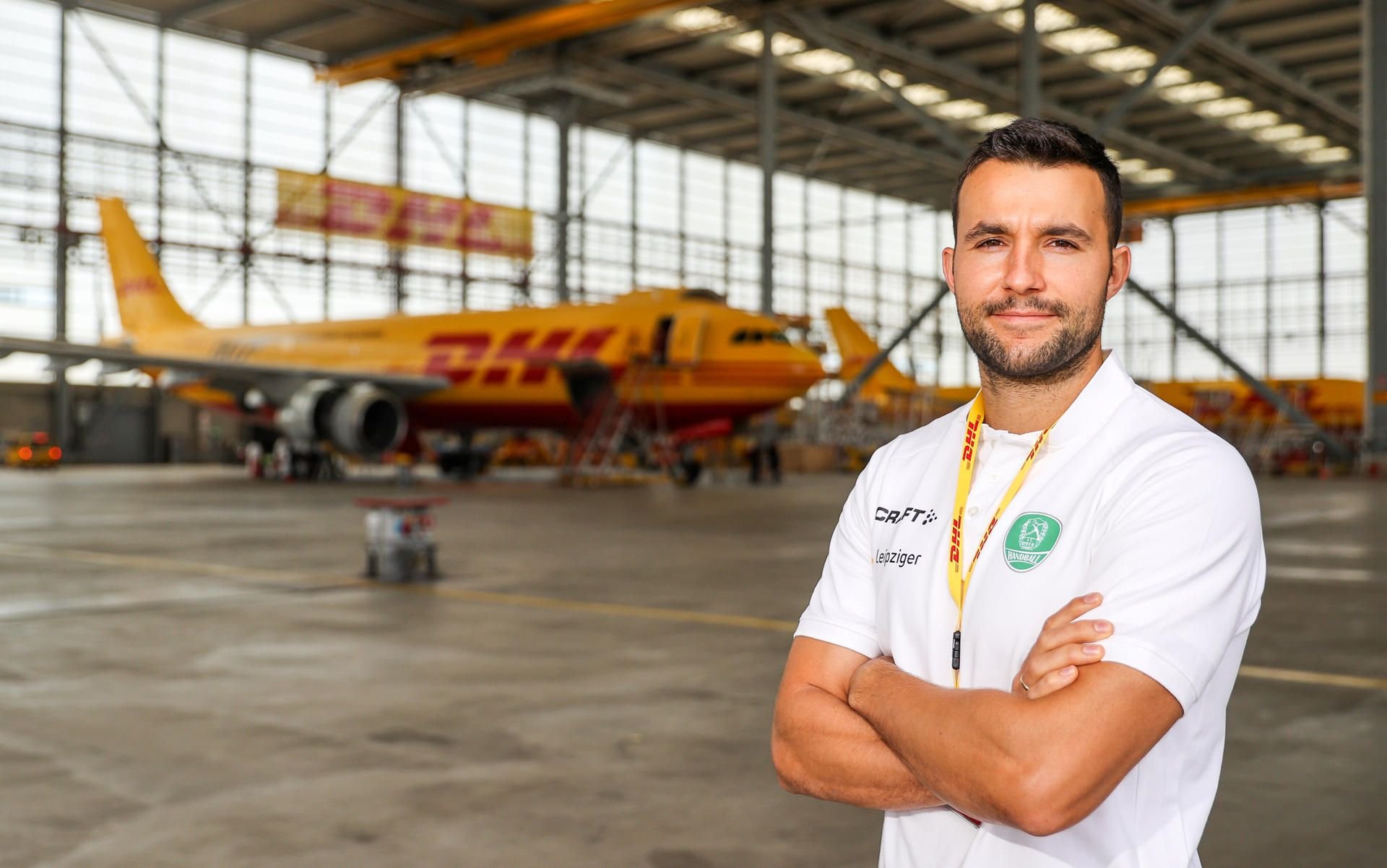 Bastian Roscheck vom SC DHfK steht im Hangar des Logistikunternehmens DHL.