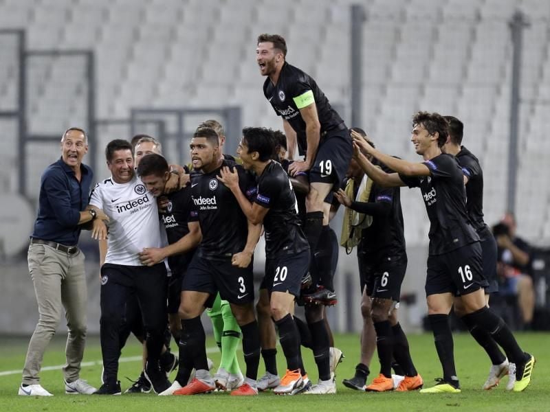Die Spieler von Eintracht Frankfurt feiern im leeren Stade Vélodrome ihren Sieg über Olympique Marseille. Foto: Claude Paris/AP