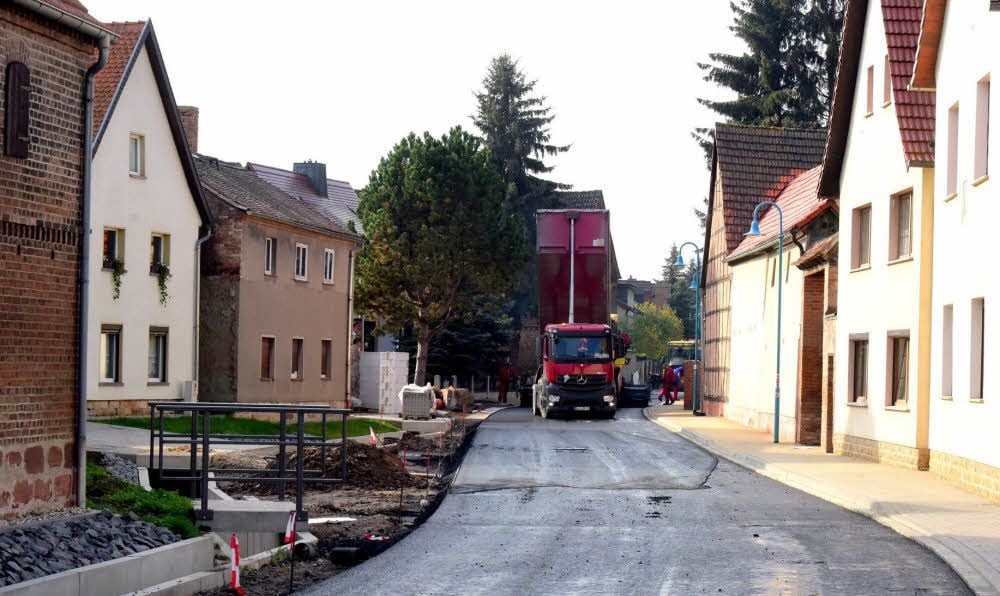 Ein Blick in die Lobitzscher Straße mit ihrer neuen Schwarzdecke, dem sanierten Graben und neuen Brücken auf die Grundstücke.