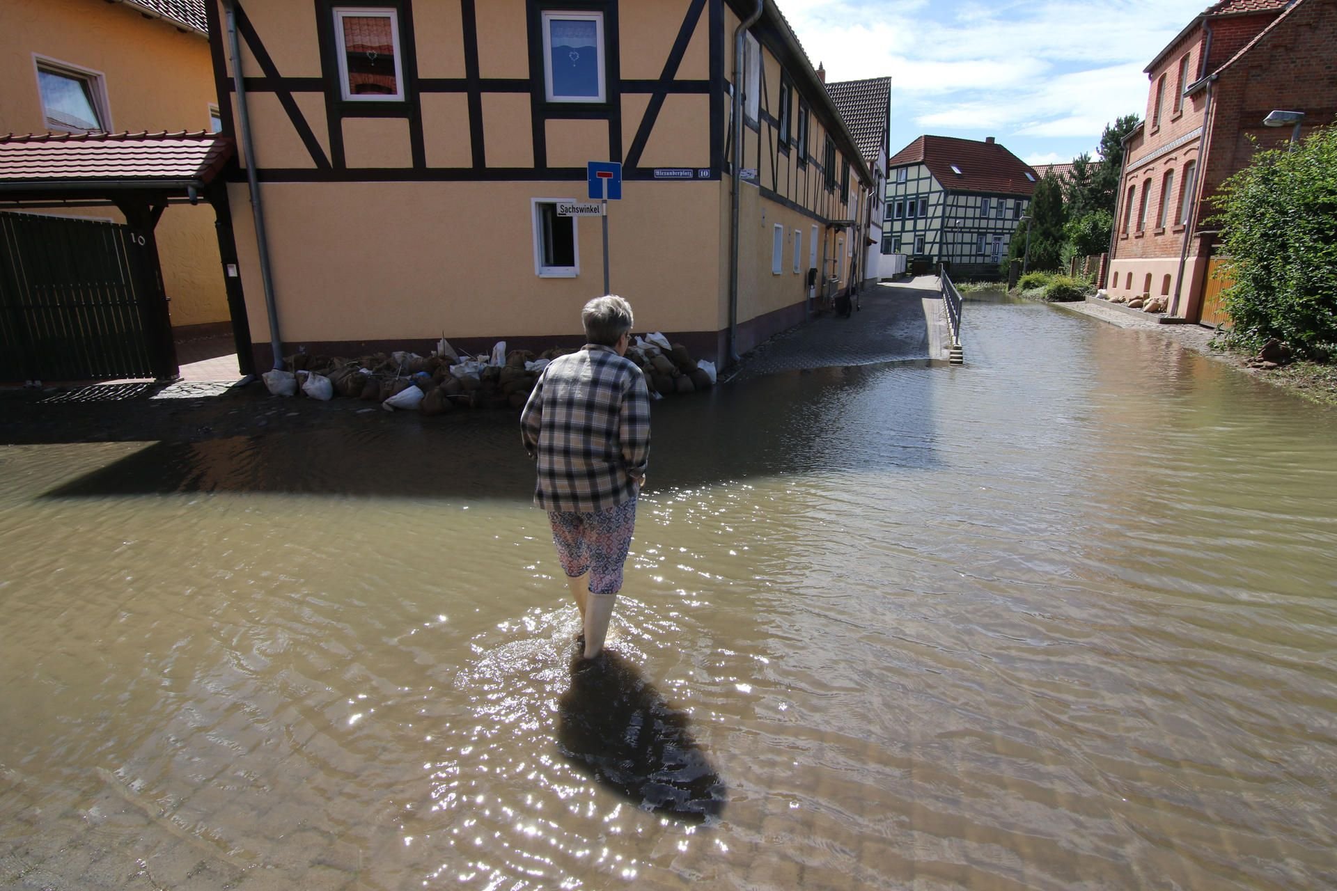 Eine Passantin überquert am 29.07.2017 in Harsleben (Sachsen-Anhalt) eine überflutete Straße.