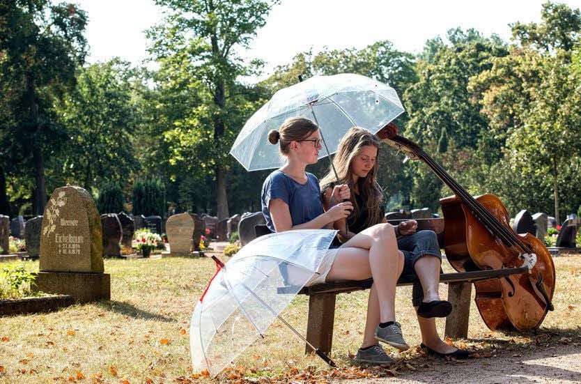 Clara Griehl aus Axien (l.) und Viviane Hammermüller aus Würzburg gönnten sich nach ihrem Eröffnungskonzert auf dem Friedhof Jessen eine kleine Ruhepause und ließen dabei die über die Regenschirme eingespielten Klanginstallationen auf sich wirken.