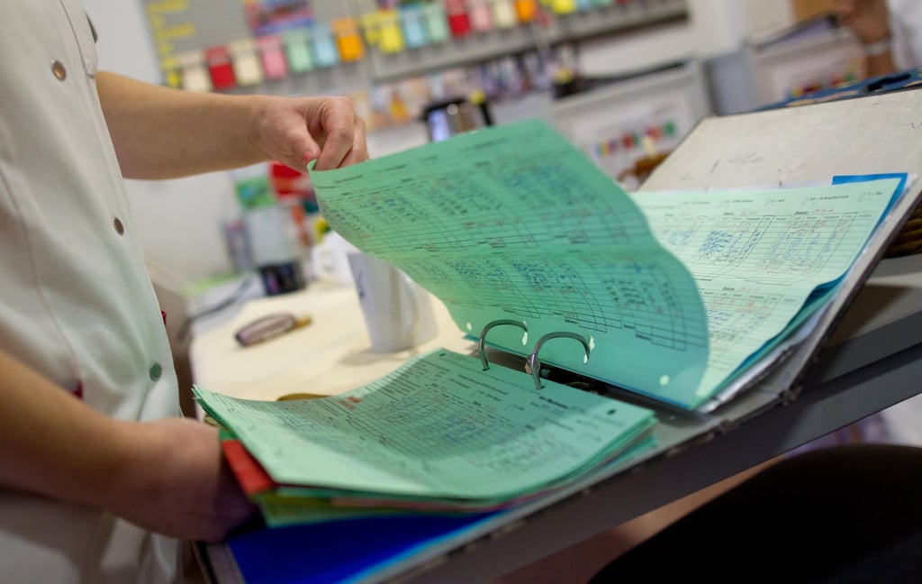 Eine Altenpflegerin in einem Pflegeheim für demenzerkrankte Menschen schaut sich einen Ordner mit Patientenakten an.