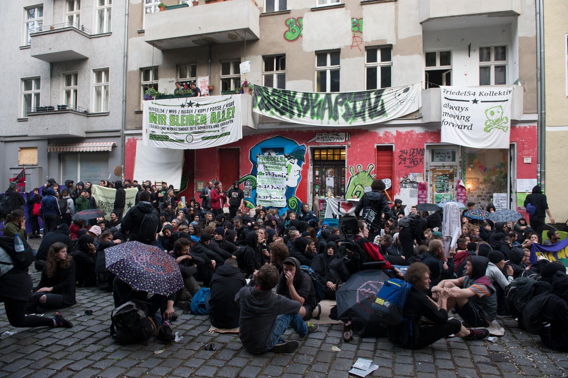 Demonstranten sitzen in Berlin auf der Straße vor dem Haus Nr. 54 in der Friedelstraße in Neukölln.