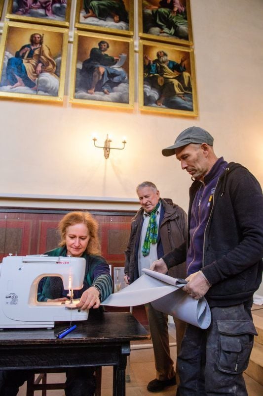 Restauratorin Andrea Himpel vernäht mit Hilfe von Marian Romanus den Stoff, im Hintergrund: Sigurd Susch.