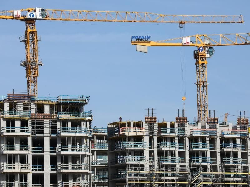 Kräne stehen auf einer Baustelle für Wohnhäuser. Viele Investoren auf dem internationalen Immobilienmarkt bevorzugen inzwischen lieber niedrigere Renditen als höhere Risiken. Foto: Christian Charisius