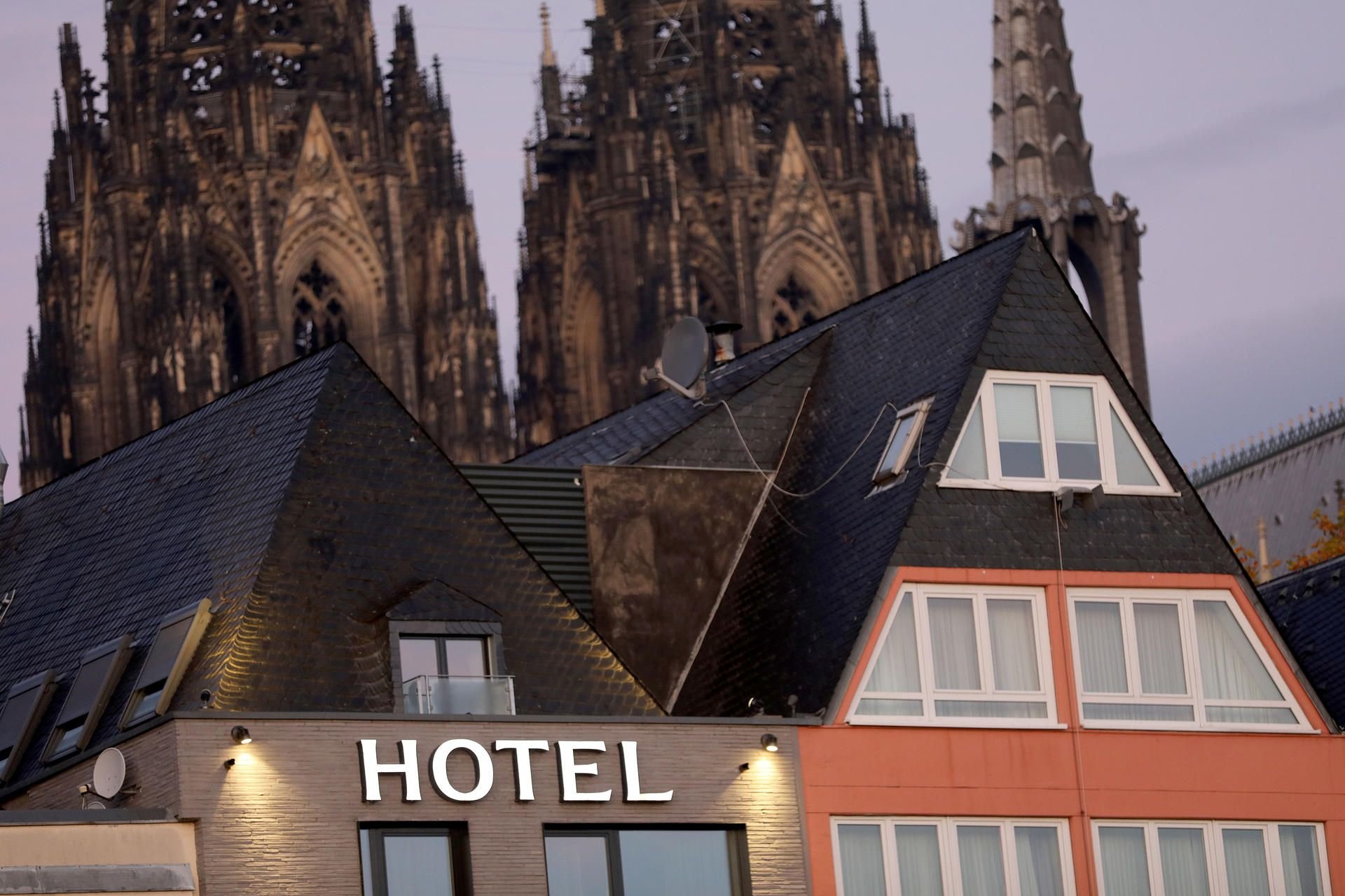 Illustration: Der leichtende Schriftzug „Hotel“ am Giebel einer Herberge vor dem Dom in Köln.