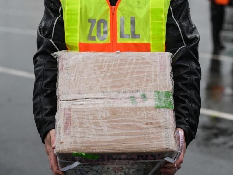 Ein Zollbeamter hält ein Paket, das im Rahmen der Kontrolle durchleuchtet wird. Foto: Andreas Arnold/dpa